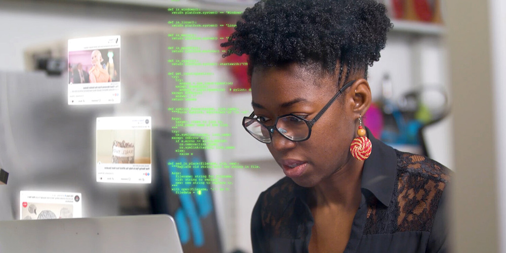MIT Media Lab researcher Joy Buolamwini working on her laptop computer, overlaid with code and social media posts