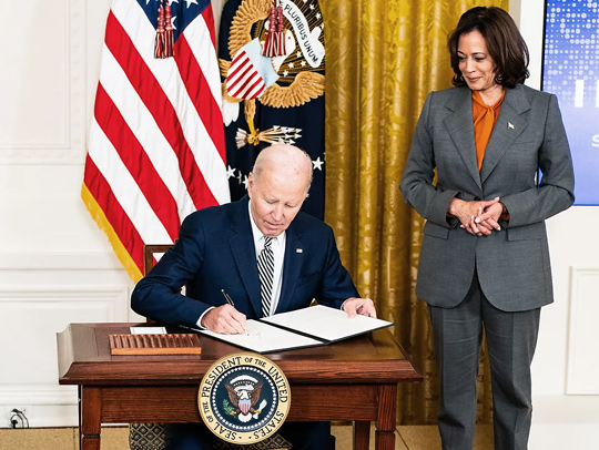A photo of President Joe Biden, sitting at a small desk bearing the presidential seal, signing an executive order on artificial intelligence. Credit: Demetrius Freeman for The Washington Post via Getty Images.