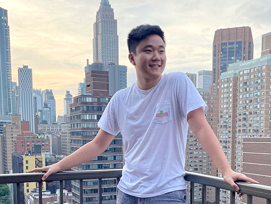 Yong Li standing on a balcomy overlooking New York City