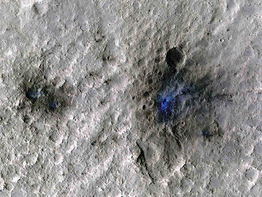 A crater formed by a meteroid impact on the surface of Mars, detected by NASA's InSight. A false-color blue area indicates where dust and soil have been disturbed. Credit: NASA/JPL-Caltech/University of Arizona.