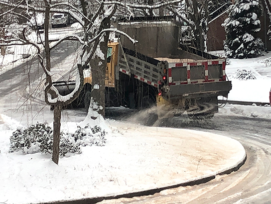 A salt truck driving down a snowy road