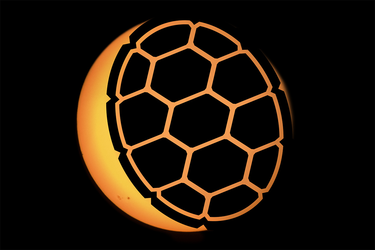 A terrapin shell eclipsing an orange sun against a black sky.