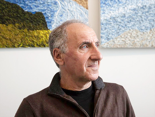 A photo of Yaser Yacoob in front of paintings by Stephanie S. Cordle
