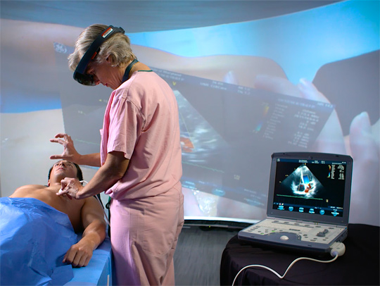 A doctor in scrubs, wearing a headset, working with a mannequin. A screen behind her shows the information she is seeing, overlaid on the mannequin.
