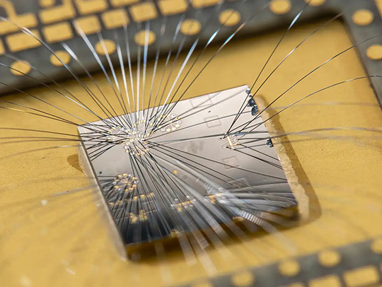 Closeup up a tiny silver computer chip with fine fillaments attached to it. Credit: John Brecher, Microsoft