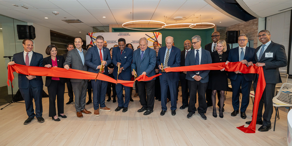 A group of VIPs, including CMNS Dean Amitabh Varshney and UMD President Darryll Pines, cutting a large red ribbon at the Institute for Health Computing's second anniversary celebration. Credit: Mark Sherwood.