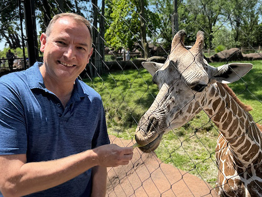 David Powell feeding a giraffe. Credit: St. Louis Zoo.