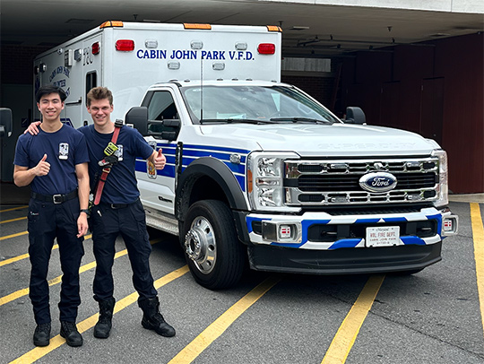 Kyle Zibell and a colleague standing beside a parked ambulance