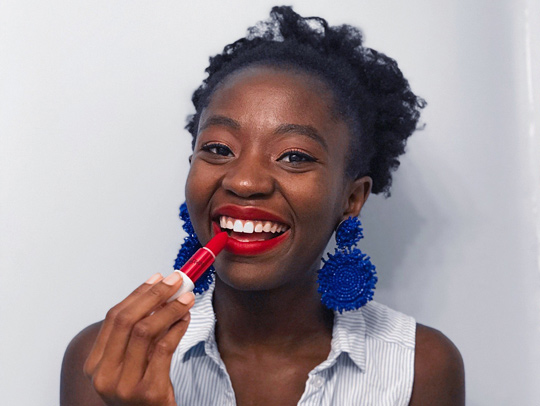 Ama Gyedu putting on bright red lipstick.