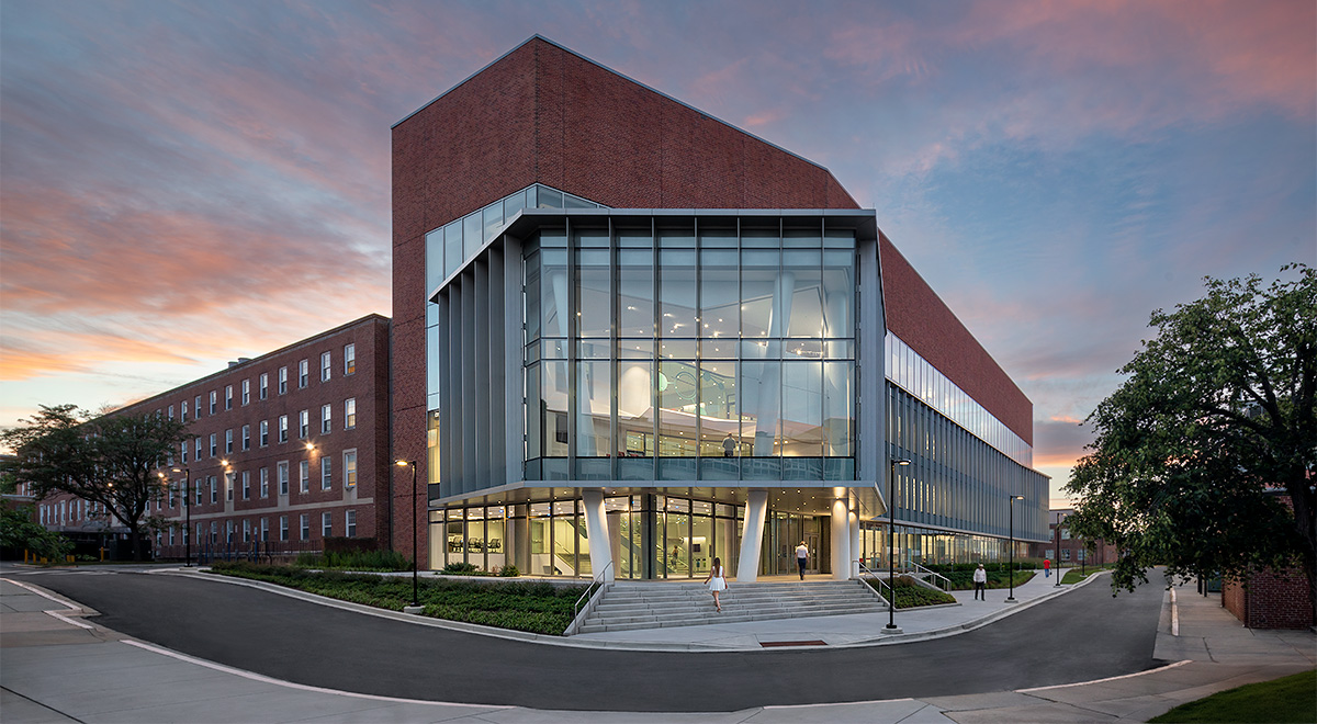A view of the new chemistry wing taken from across the street. It's sunset, and there are wispy pink and orange clouds in the sky. Through the building's large glass wall, the lobby and two more floors are visible, showing high ceilings and lofty walkways. Credit: Ballinger A view of the new chemistry wing taken from across the street. It's sunset, and there are wispy pink and orange clouds in the sky. Through the building's large glass wall, the lobby and two more floors are visible, showing high ceilings and lofty walkways. Credit: Ballinger