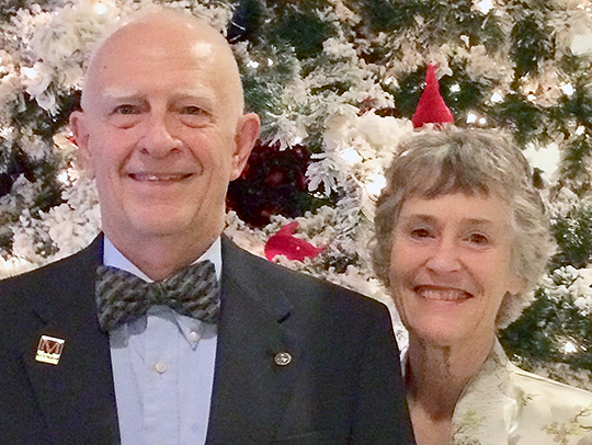 Bill Walters standing with his wife in front of a Christmas tree