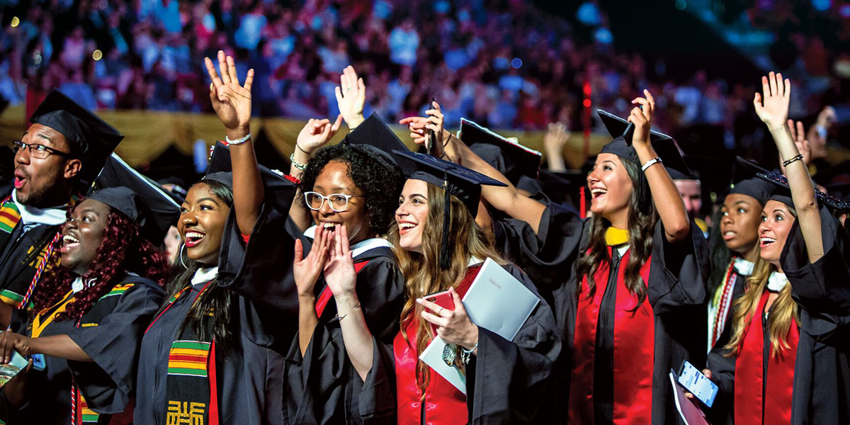A group of students in regalia, hands in the air, celebrating at commencement. Credit: Stephanie Cordle/University of Maryland