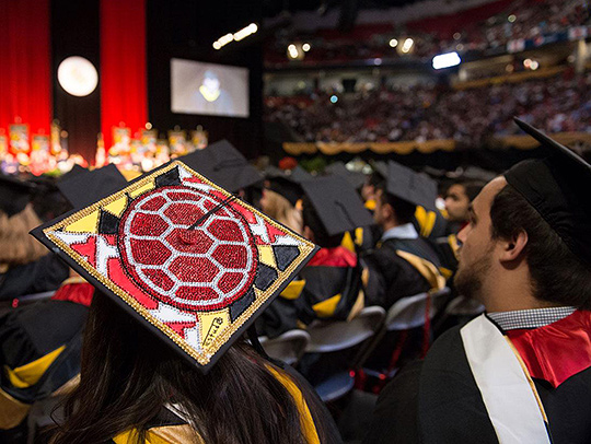 A photo of a woman wearing a Maryland-themed,  rhinestone-decorated cap at commencement, by Mike Morgan
