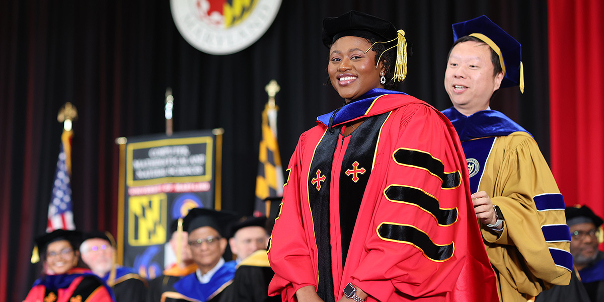 A professor hooding a CS Ph.D. student at the May 2026 commencement ceremony. Both are wearing regalia.