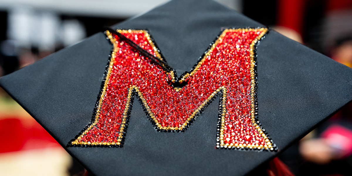 Closeup of the top of a student's mortarboard cap, which has been bejeweled with a UMD athletics-style M. Credit: Mark Sherwood Closeup of the top of a student's mortarboard cap, which has been bejeweled with a UMD athletics-style M. Credit: Mark Sherwood