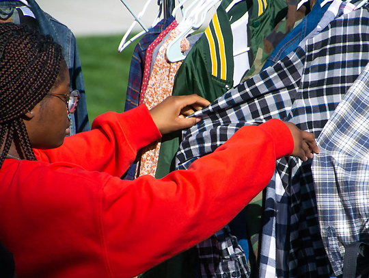 A woman looking through a rack of clothing.