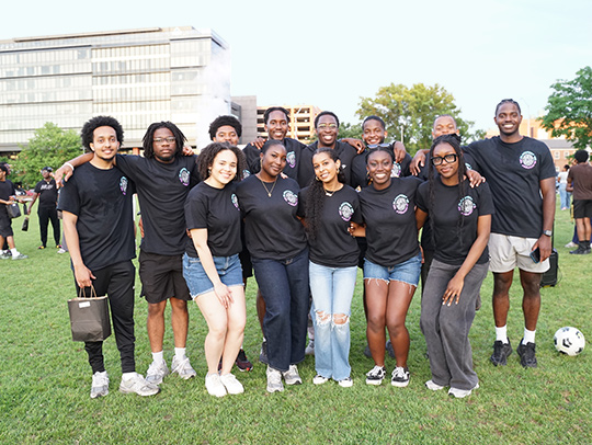 A group photo of the members of code:BLACK. They are outside on a lawn.
