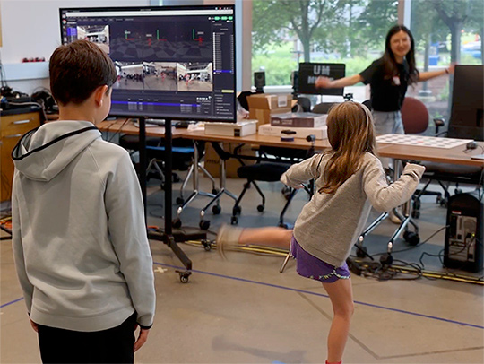 A little girl dances at a computer science exhibit at Maryland Day 2025.