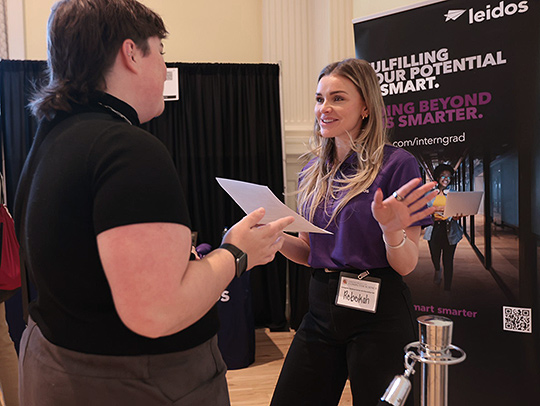 Senior computer science major Wren Poremea speaks with a Leidos representative at the spring career fair.