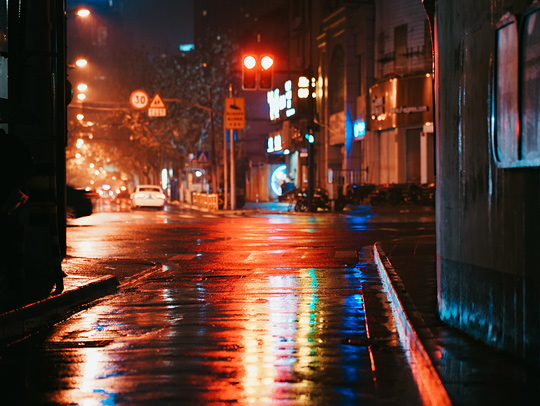 A dark, wet, empty street with red lights. Photo credit: Edward Xu.