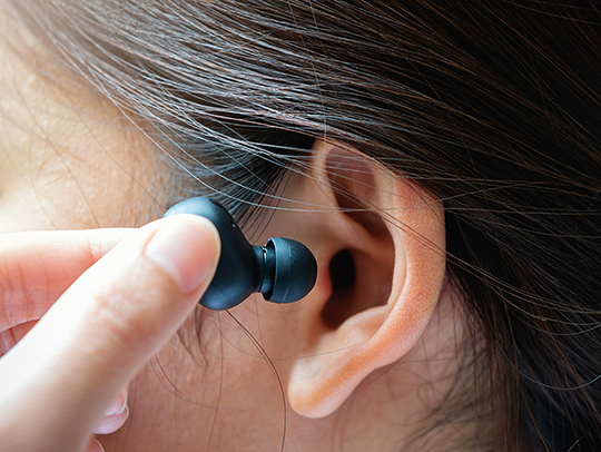 An earbud in an ear. Credit: Adobe Stock