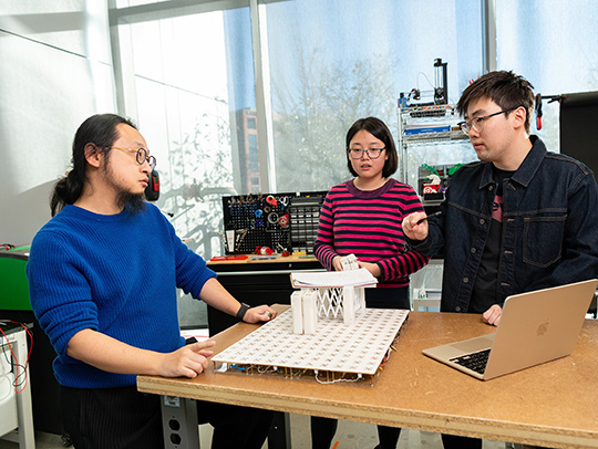 Huaishu Peng and CS graduate students talking in a lab.