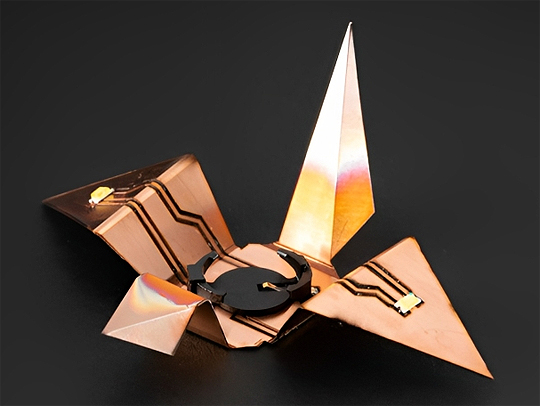 A flexible circuit made with the fibercuit technique. It looks somewhat like an origami crane made of copper, with electrical components.