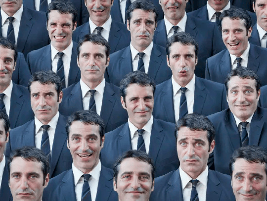 A crowd of faces of the same man, each with a different expression on it. Credit: Getty Images.