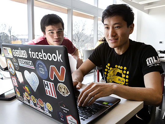 Two young men at a desk using a laptop. Credit: John T. Consoli.