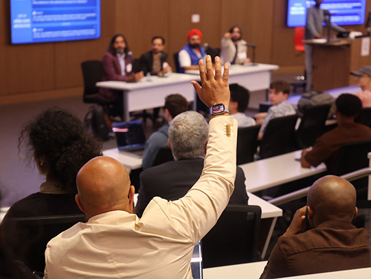 A man raising his hand to ask a question of the panel at the Hatchery kickoff event.