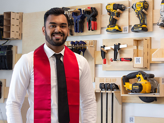 Hrithik Bansal standing in front of a tool wall he built for the UMD Sandbox.