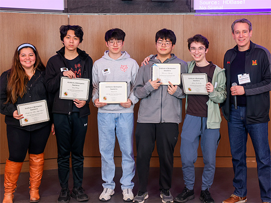 A group of high school students in the Iribe Center, holding certificates