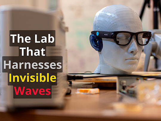 A dummy head wearing smart glasses, sitting on a tabletop in a lab