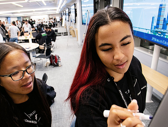 Two young women participants at the JPMorgan Code for Good Hackathon. Credit: J.P. Morgan.
