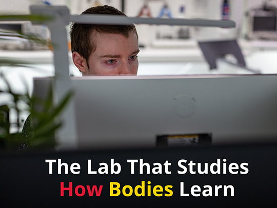 A young man behind a computer screen in the Embodied Dynamics Laboratory