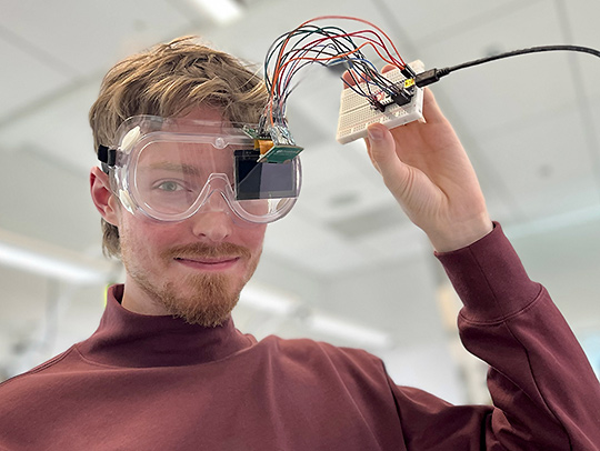 Logan Stevens wearing safety glasses on which an eyepiece has been attached.