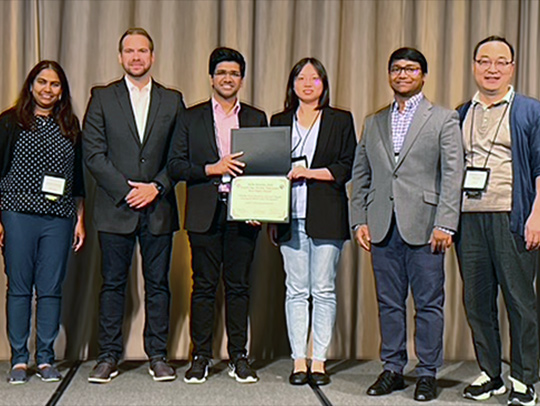 UMD computer science team receiving an award for their design of a a navigation sensor for mini robots