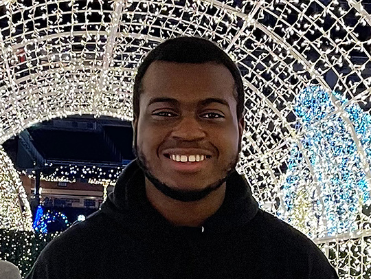 Nathan Addai standing under a large, tunnel-like trellis covered with tiny lights.