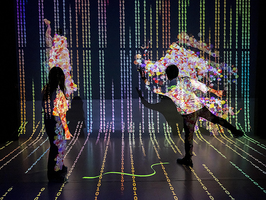 Students interacting with a brightly-colored, projected art piece created by the Immersive Media Design Program at UMD's NextNow festival.