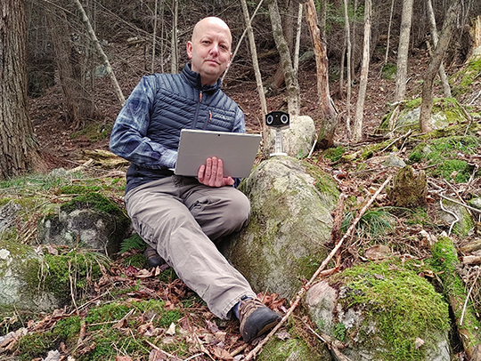 Peter Ersts sitting in the forest with his laptop
