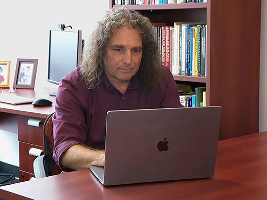 Philip Resnik sitting at a desk in front of a laptop