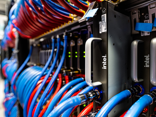 A closeup image of a server rack, showing many blue and red cables and Intel chips.
