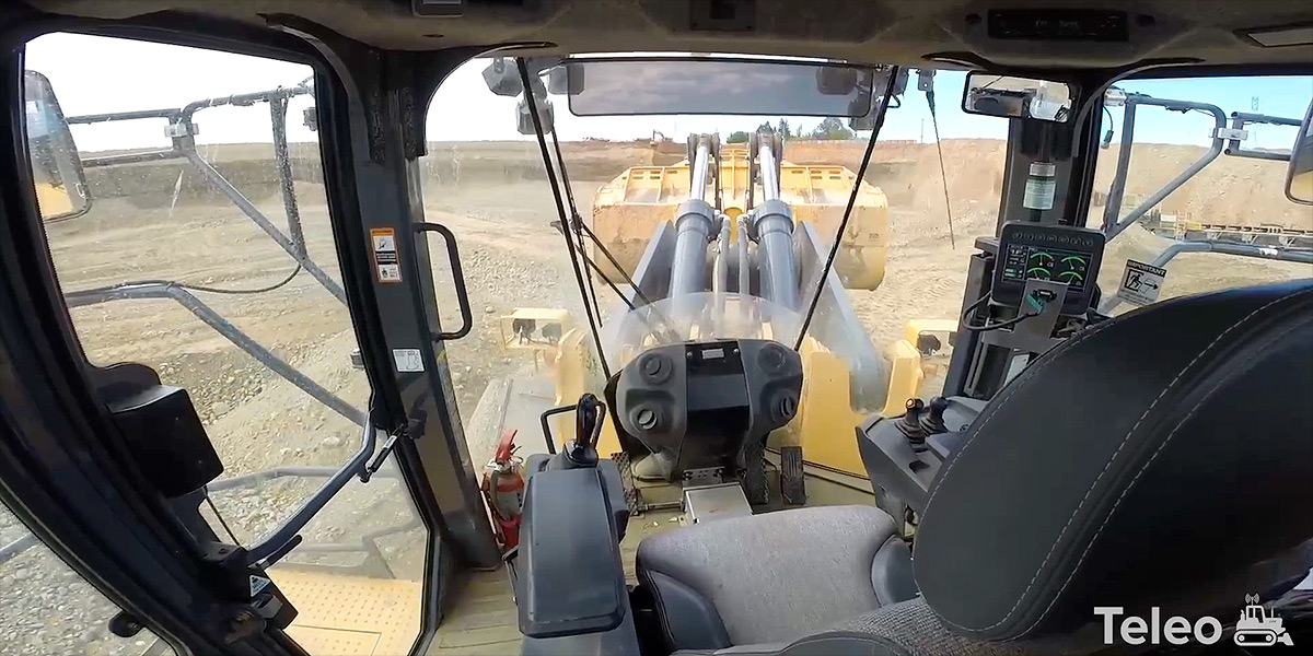 No one's at the wheel! View from inside the cab of large, heavy-duty contruction vehicle, a wheel loader, driving itself around a contruction site.