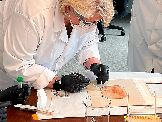 To determine if famed scientist and artist Leonardo da Vinci drew the 'Holy Child,' University of Maryland cell biology and molecular genetics Assistant Professor Norberto Gonzalez-Juarbe and forensic biologist Rhonda Roby collected microbial collect swabs from the palm-sized red chalk sketch. (Photo by Marguerite Mangin)