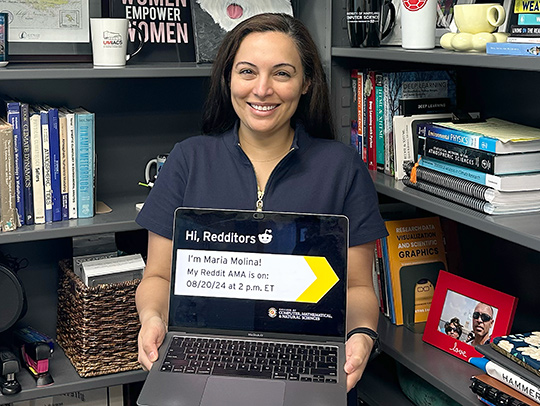 Maria Molina in her office, holding a laptop, getting ready for her Reddit Ask Me Anything session. Credit: Katie Bemb.