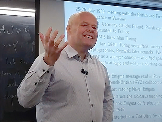 Zbigniew Błocki in front of screen at a lecture, gesturing and smiling