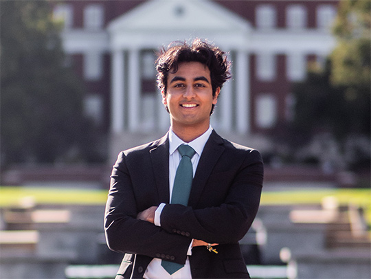 Dhruv Dewan standing on the UMD mall, with the mall fountain and admin building in the background