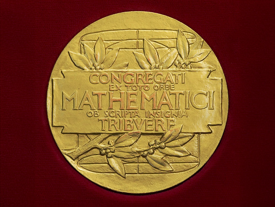 The reverse of the Fields Medal, a golden coin with laurel leaves and a Latin inscription on it. The text reads, Congregati ex toto orbe mathematici ob scripta insignia tribvere.