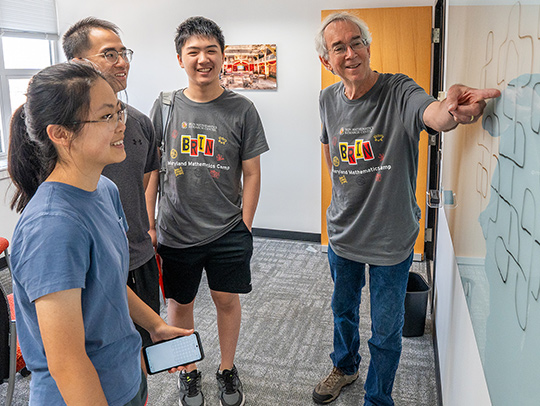 Lawrence Washington at a whiteboard with three students. Credit: Mark Sherwood.