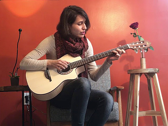 A still from a video of Sheyda Peyman playing an acoustic guitar. Credit: Sheyda Peyman